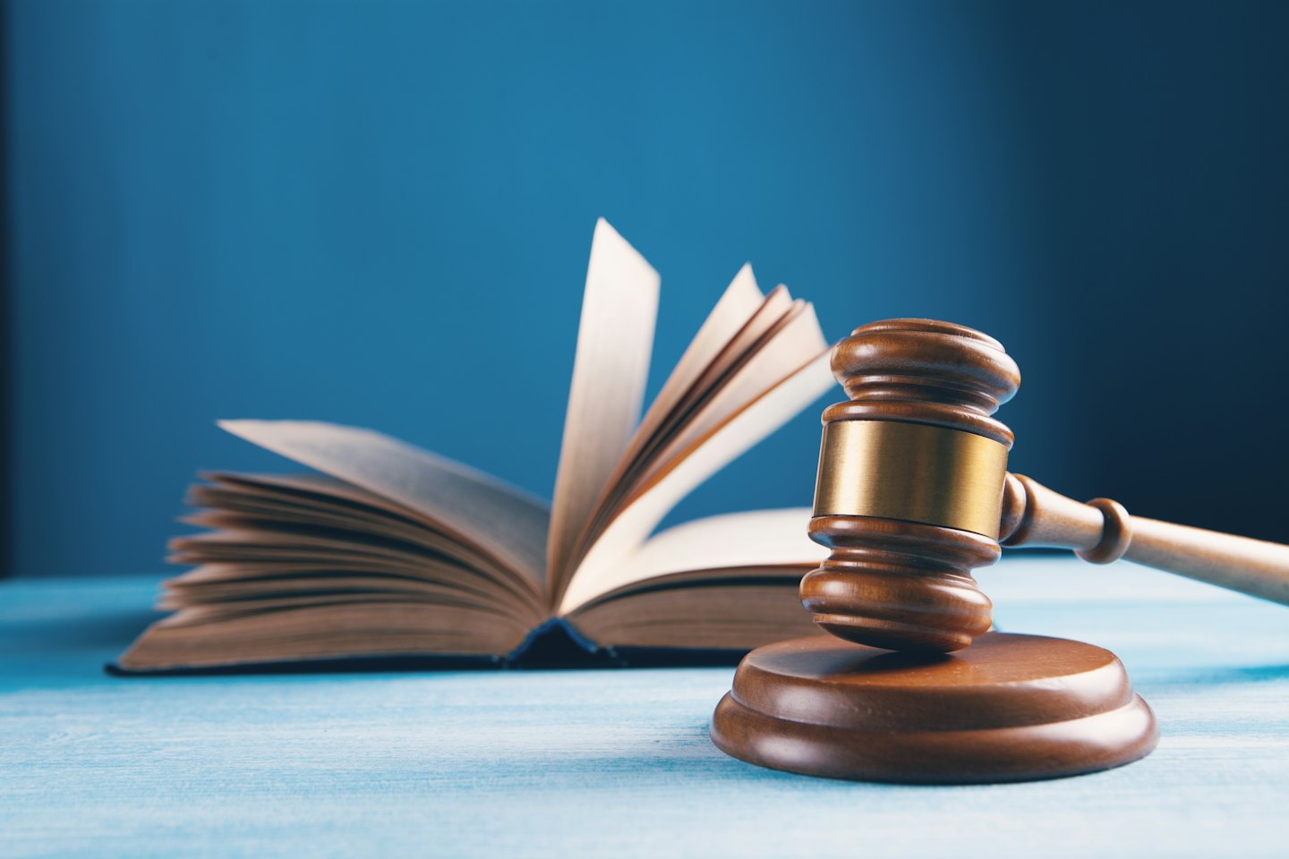 A wooden gavel rests on a book and table.